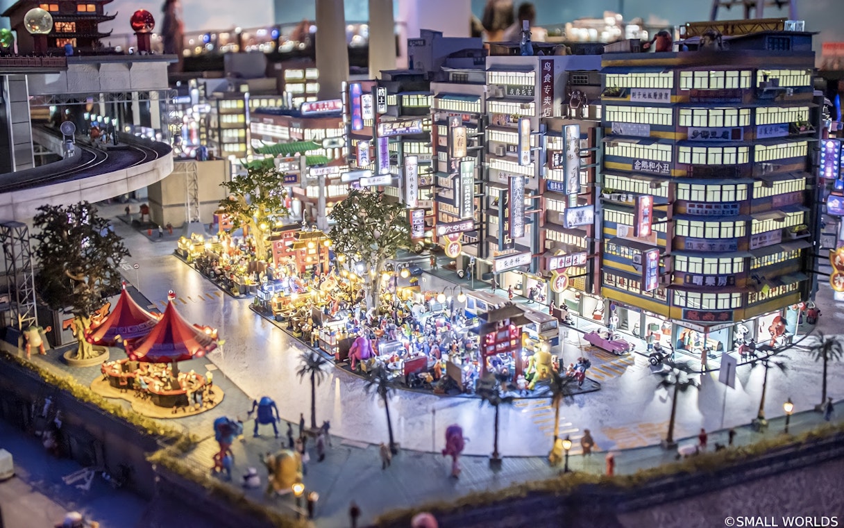 Miniature cityscape with bustling street market at Small Worlds Tokyo.