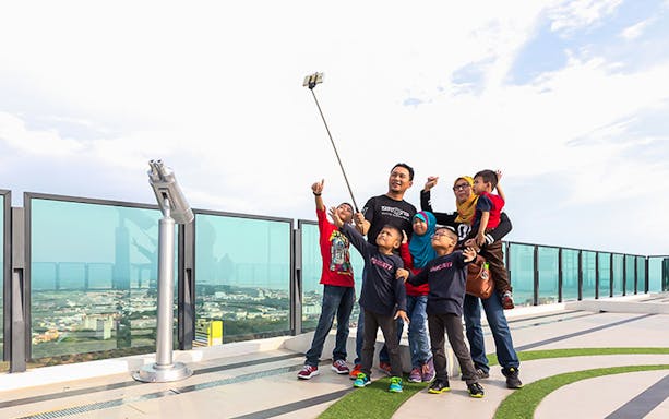 Family taking a selfie on the observation deck of The Shore Sky Tower, overlooking the cityscape.