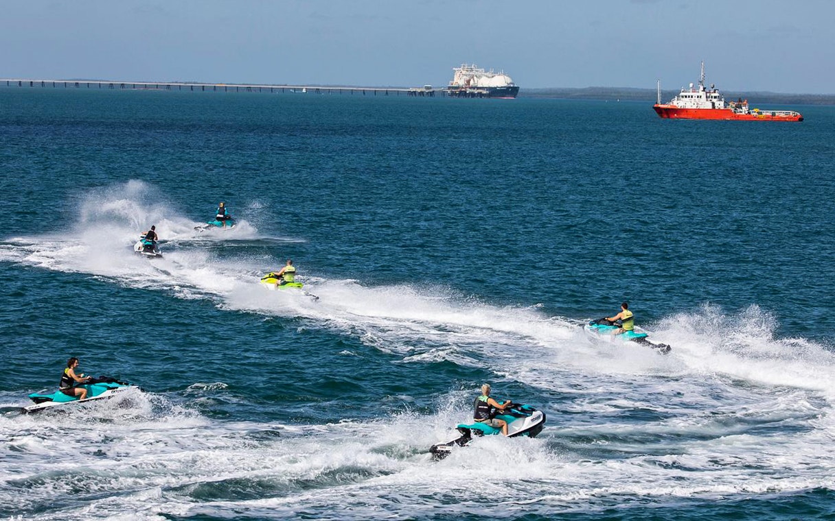 Jet skis speeding across the ocean in Darwin with ships in the background.