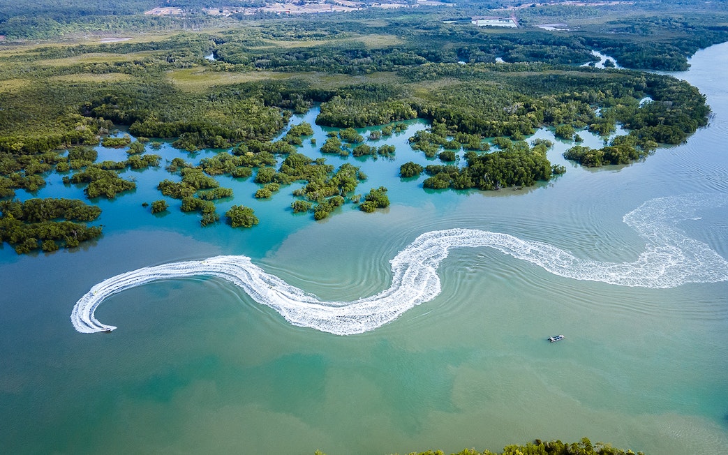 Jet ski creating wake trails in mangrove waters, Darwin.
