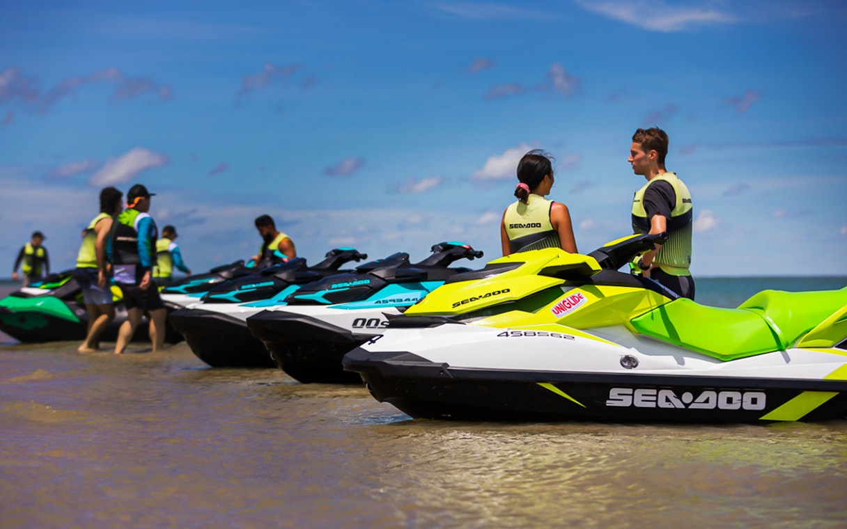 Jet skis lined up on the beach with people preparing for a tour in Darwin.