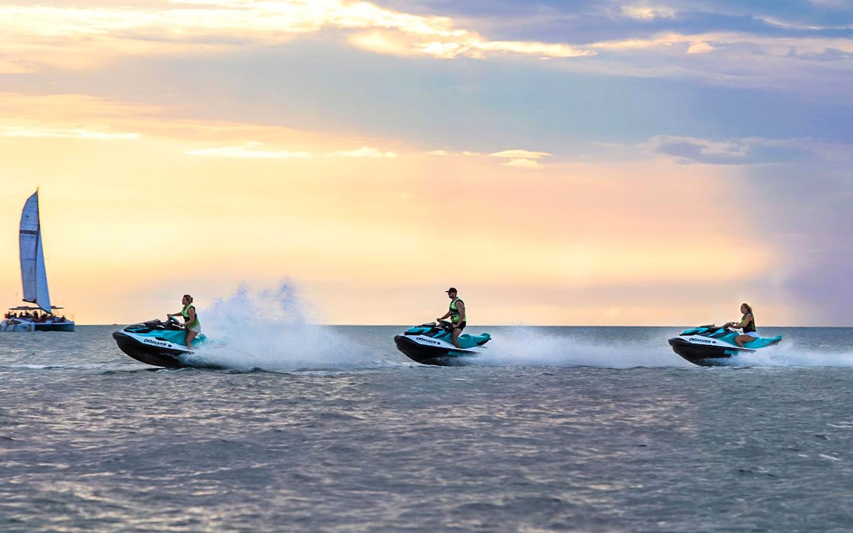 Jet skis speeding across the water at sunset during a tour in Darwin.
