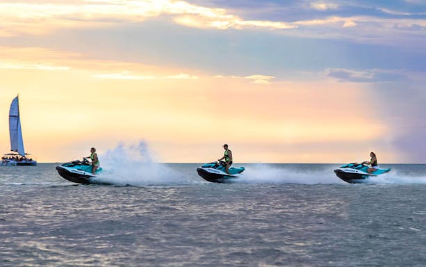 Jet skis speeding across the water at sunset during a tour in Darwin.