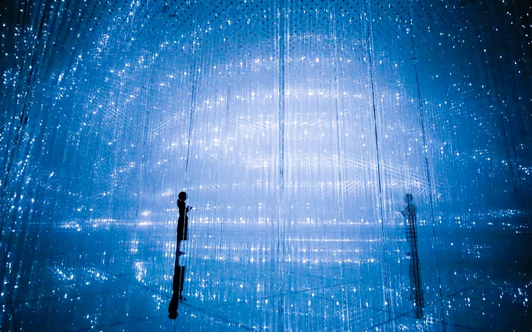 Visitors at TeamLab Planets Tokyo in a digital art installation with blue lights.