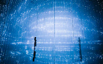 Visitors at TeamLab Planets Tokyo in a digital art installation with blue lights.