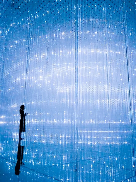 Visitors at TeamLab Planets Tokyo in a digital art installation with blue lights.