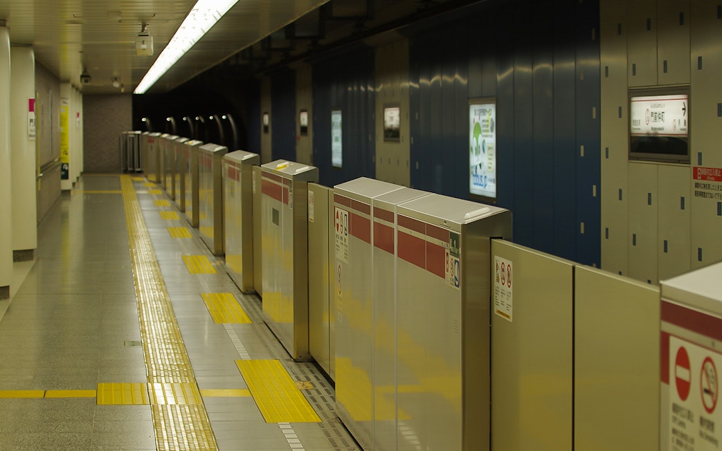 Tokyo subway platform with ticket barriers and yellow tactile paving.