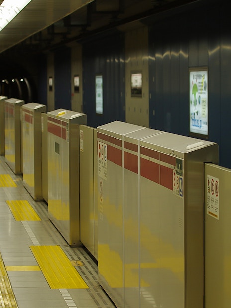 Tokyo subway platform with ticket barriers and yellow tactile paving.