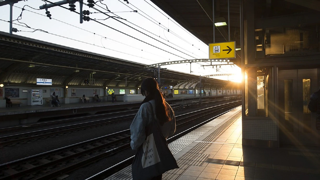Tokyo subway platform at sunset with a person waiting for a train.