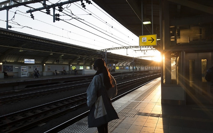 Tokyo subway platform at sunset with a person waiting for a train.