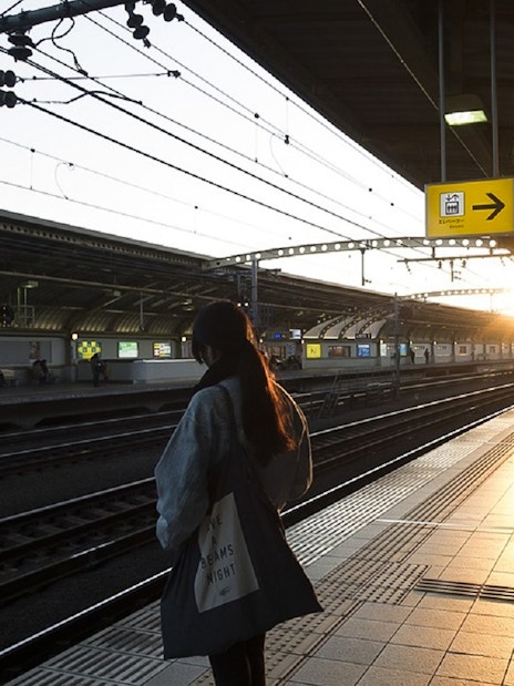Tokyo subway platform at sunset with a person waiting for a train.
