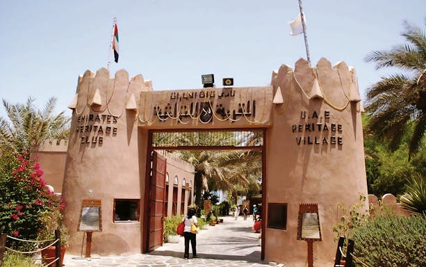 Entrance to UAE Heritage Village in Abu Dhabi with visitors exploring the site.