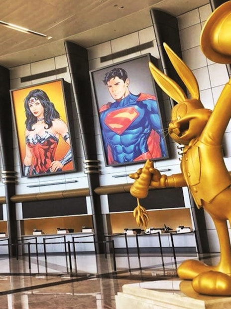 Warner Bros. World™ Abu Dhabi entrance with superhero posters and golden cartoon statue.