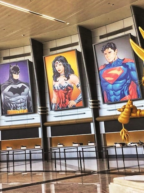 Warner Bros. World™ Abu Dhabi entrance with superhero posters and golden cartoon statue.