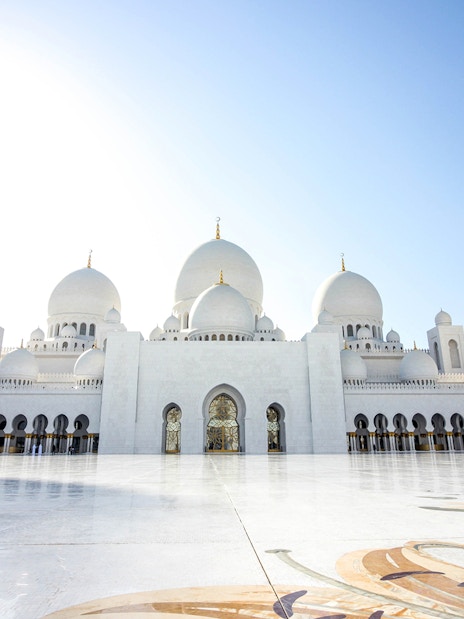 Sheikh Zayed Mosque in Abu Dhabi with white domes and minarets under a clear blue sky.