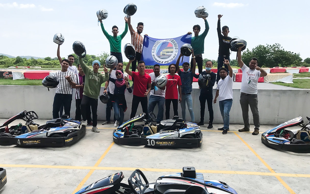 Group celebrating at Go-Kart Langkawi, Morac Adventure Park, holding helmets near karts.