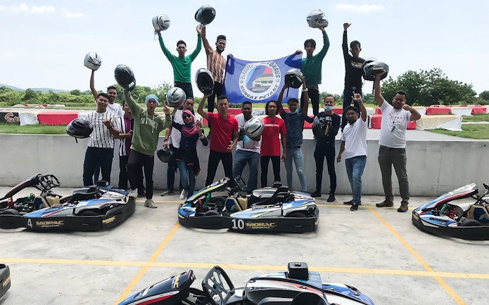 Group celebrating at Go-Kart Langkawi, Morac Adventure Park, holding helmets near karts.