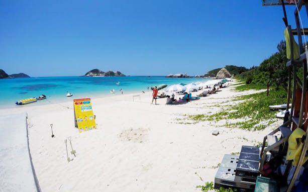 Aharen Beach with sunbathers, umbrellas, and water activities in Okinawa, Japan.