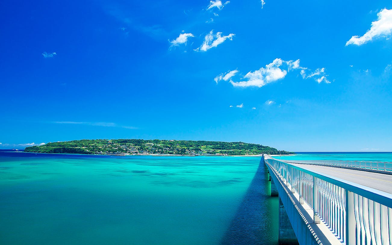 Bridge over turquoise waters leading to Okinawa island, Japan, on a clear day.