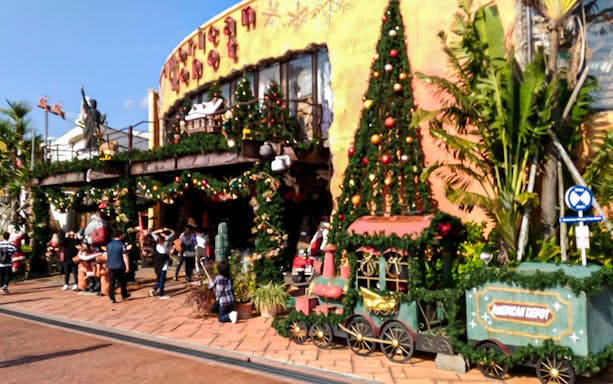 American Village decorated for Christmas with festive train and visitors, Okinawa bus tour.