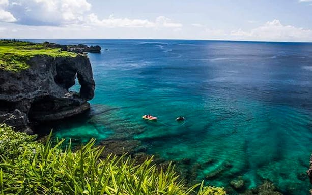 Coastal view of Manzamo cliffs in Okinawa with clear blue water and a kayak.