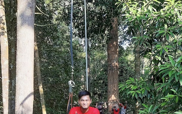 Person ziplining through forest at Skytrex Adventure Melaka.