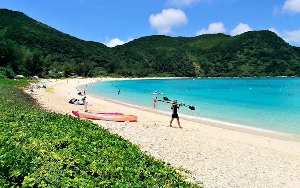 Seabathing at Tokashiku Beach with kayaks and swimmers in clear blue water.