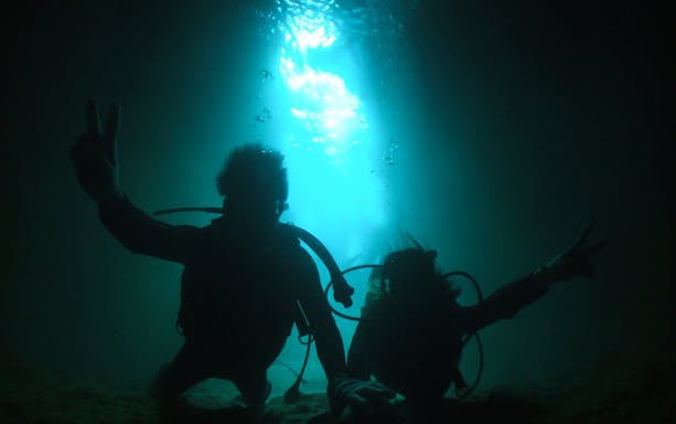 Scuba divers exploring the illuminated Blue Cave.
