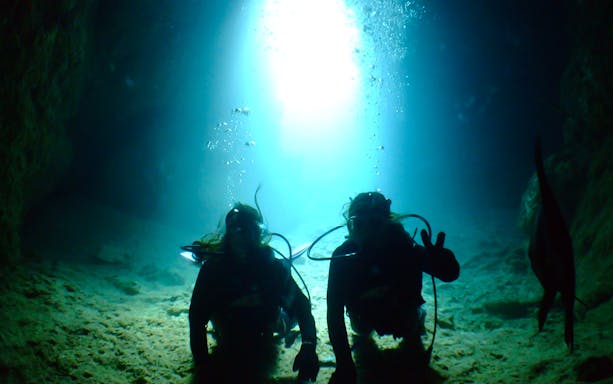 Scuba divers exploring Blue Cave underwater.