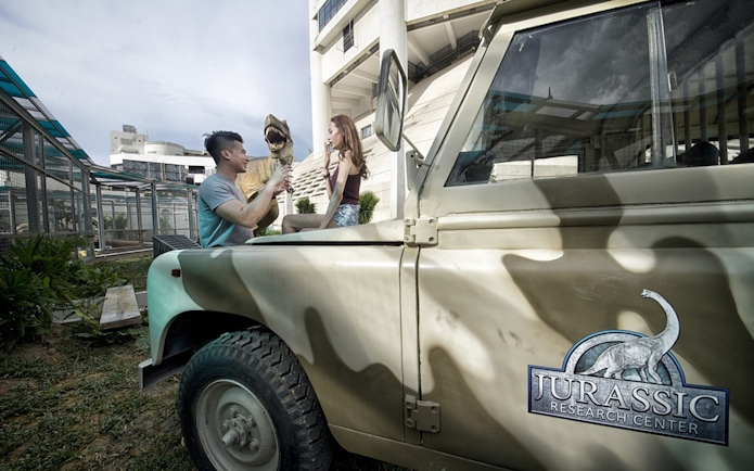 Visitors interacting with a dinosaur model at The Top Penang Jurassic Research Centre.