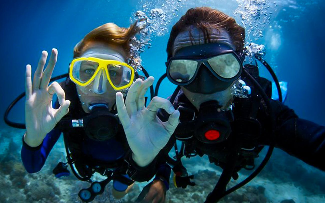 Scuba divers underwater giving OK sign in Dubai.