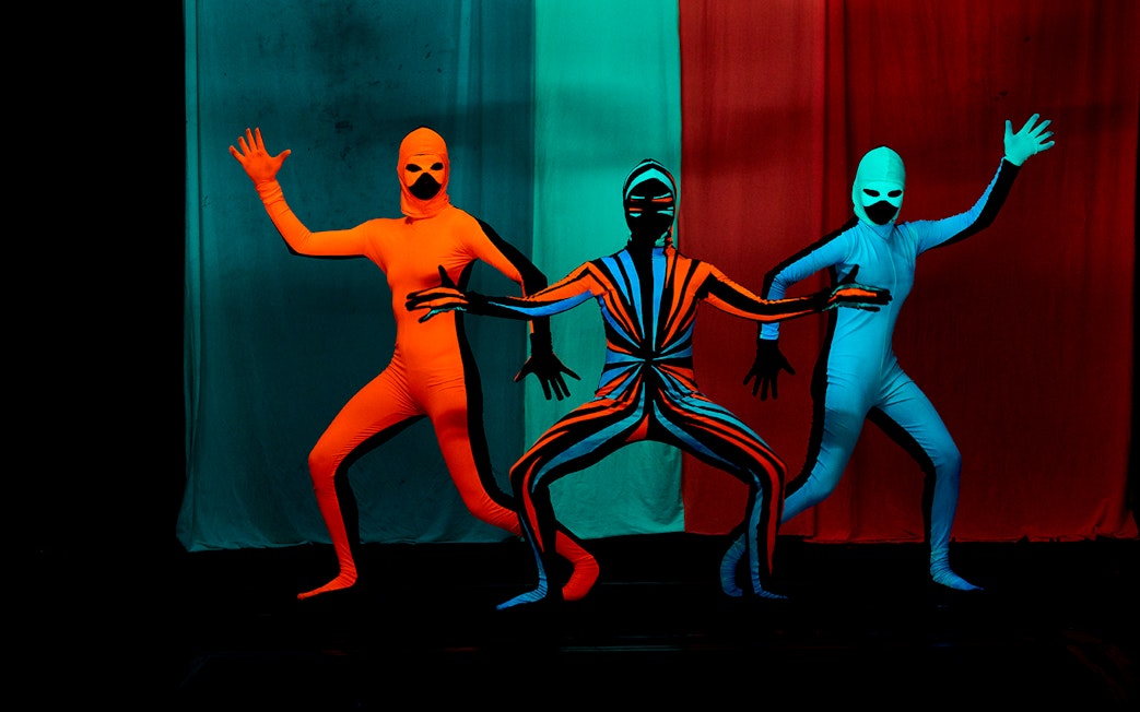 Performers in vibrant costumes at WOW Show Black Light Theater.