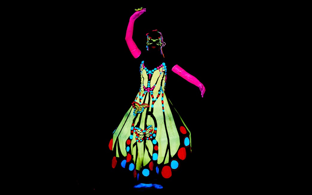 Performer in colorful costume at WOW Show Black Light Theater.