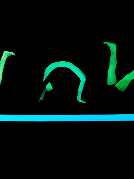 Glowing green figures performing at WOW Show Black Light Theater.