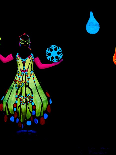 Performer in colorful costume at WOW Show Black Light Theater.