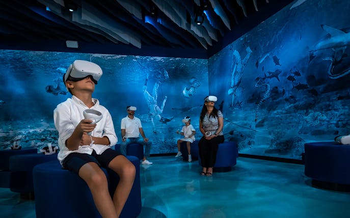 Visitors using VR headsets in an underwater-themed room at Al Shindagha Museum.