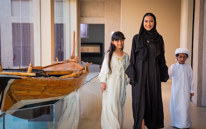 Visitors exploring traditional boat exhibit at Al Shindagha Museum.