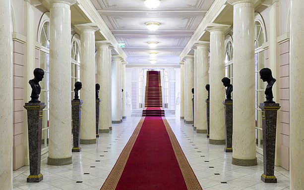 Marble hallway with busts and red carpet at Albertina Museum, Vienna.