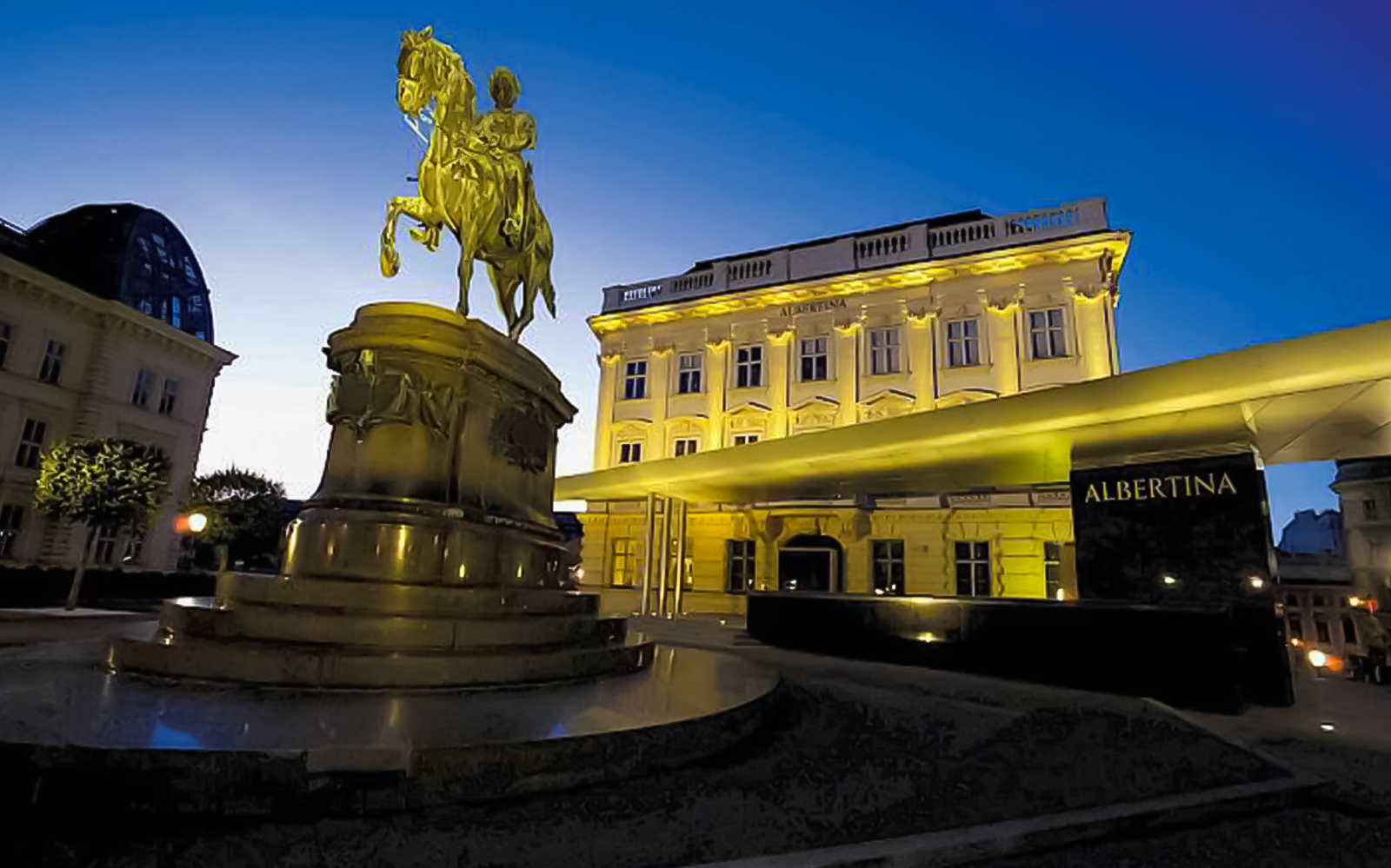 Goldene Reiterstatue vor dem beleuchteten Albertina Museum in Wien bei Abenddämmerung