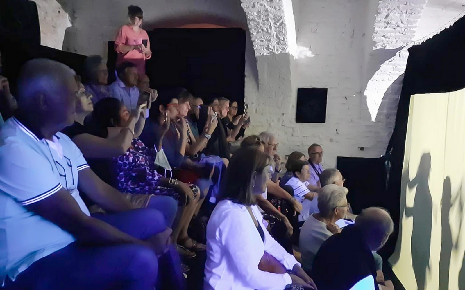 Audience watching Magic Phantom black light theatre performance.