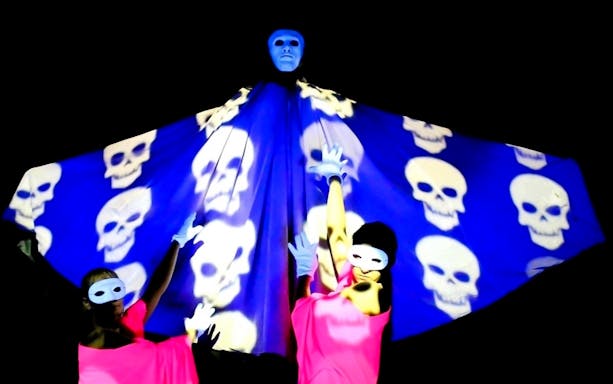 Performers in masks and gloves with skull projections at Magic Phantom Black Light Theatre.