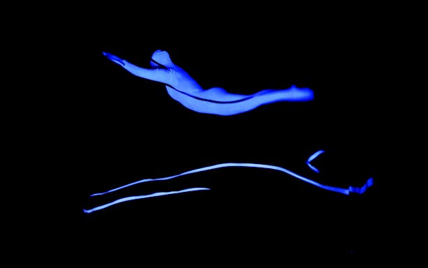 Performer in blue light at Magic Phantom Black Light Theatre.