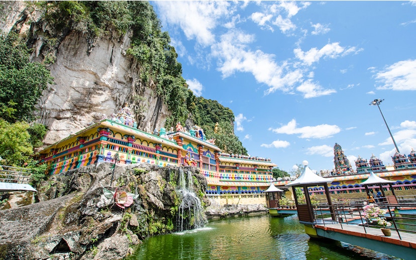 Colorful temple facade at Batu Caves with limestone cliffs and blue sky, Malaysia.