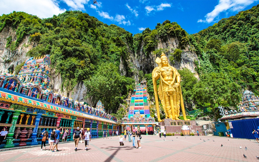 Batu Caves entrance with golden statue and colorful temple facade, Malaysia.