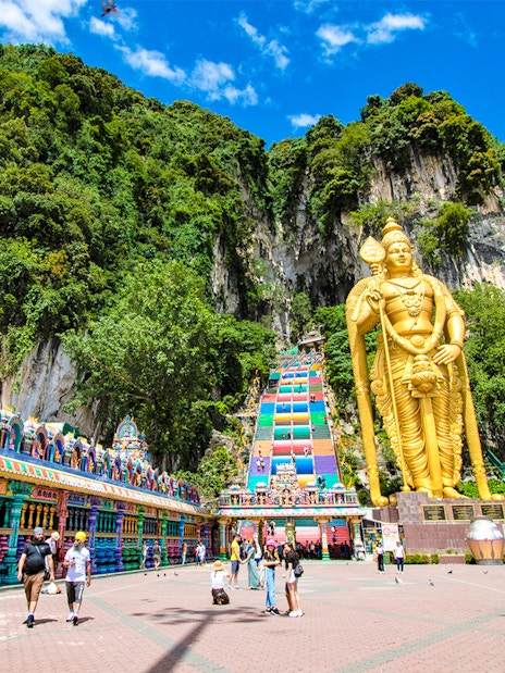 Batu Caves entrance with golden statue and colorful temple facade, Malaysia.