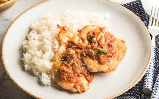 Grilled chicken with tomato sauce and rice on a plate.