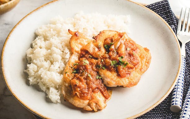 Grilled chicken with tomato sauce and rice on a plate.