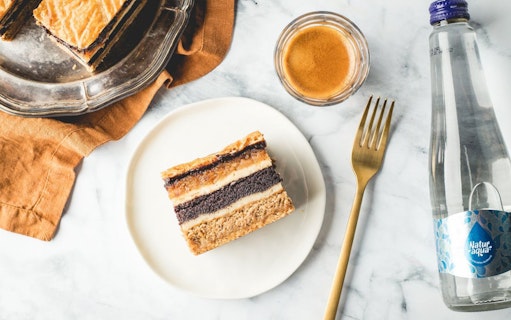 Hungarian dessert slice with coffee and water, related to Kazinczy Synagogue tour in Budapest.
