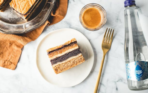Hungarian dessert slice with coffee and water, related to Kazinczy Synagogue tour in Budapest.
