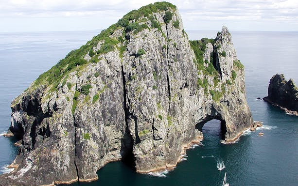 Hole in the Rock formation in Bay of Islands, New Zealand, viewed from a small tour boat.